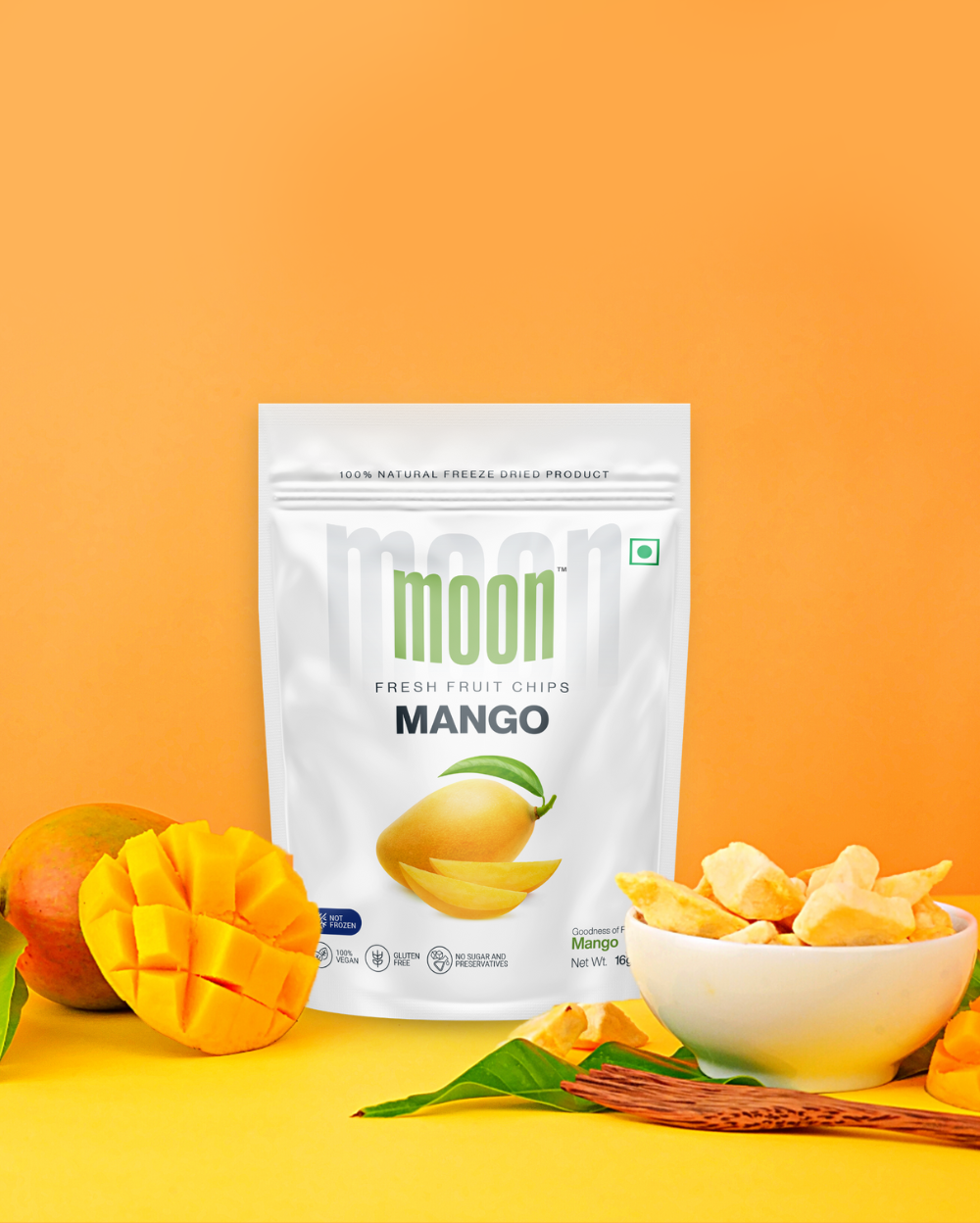 Packaged Moon Freeze Dried Strawberry + Mango fruit chips and freeze-dried strawberry slices displayed with fresh mango slices on a vibrant orange background, offering a healthy snack option.
