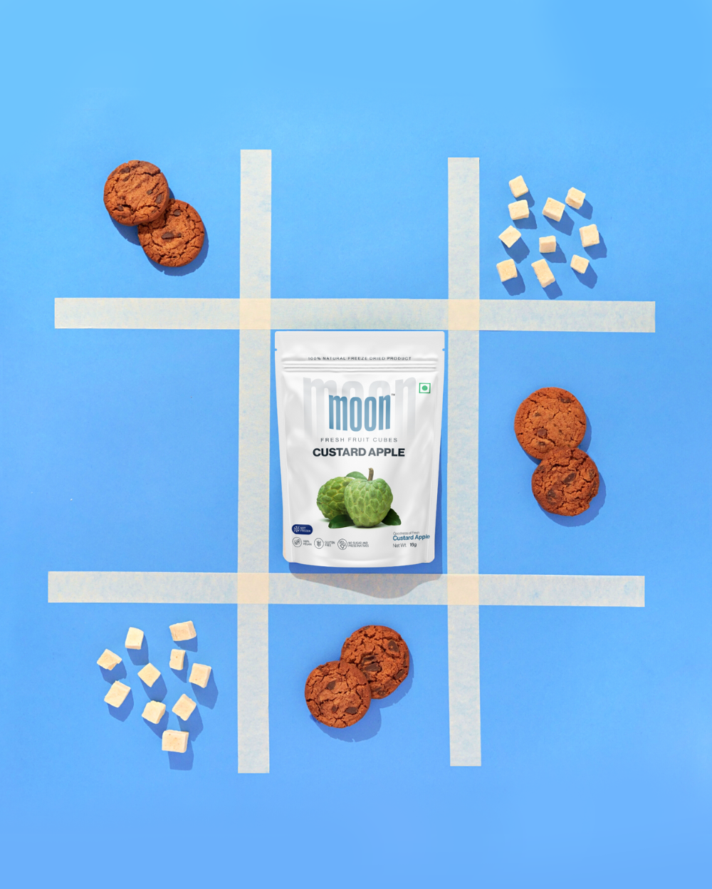 freeze-dried Custard Apple cubes arranged creatively with cookies on a vibrant blue grid, the product as a delicious and healthy snack option, perfect for pairing with other treats.