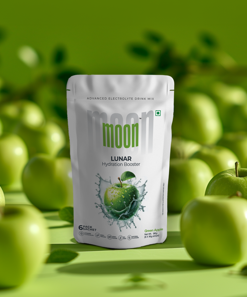Package of Moon Freeze Cosmic Bulk Packs - Mega Hydrate Edition electrolyte drink mix with a green apple flavor, surrounded by fresh apples and strawberry cubes on a matching green background from MOONFREEZE FOODS PRIVATE LIMITED.