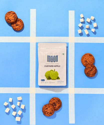  freeze-dried Custard Apple cubes arranged creatively with cookies on a vibrant blue grid, the product as a delicious and healthy snack option, perfect for pairing with other treats.