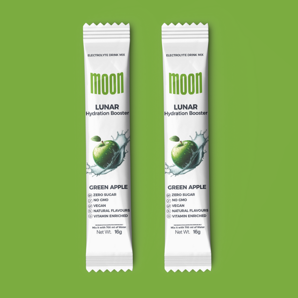 Two sachets of Moon Lunar Green Apple Hydration Stick Pack of 2 by MOONFREEZE FOODS PRIVATE LIMITED, each 16g, against a vibrant green background. The packaging highlights its features: zero sugar, non-GMO, vegan, natural flavors, vitamin enriched with essential electrolytes for optimal hydration.