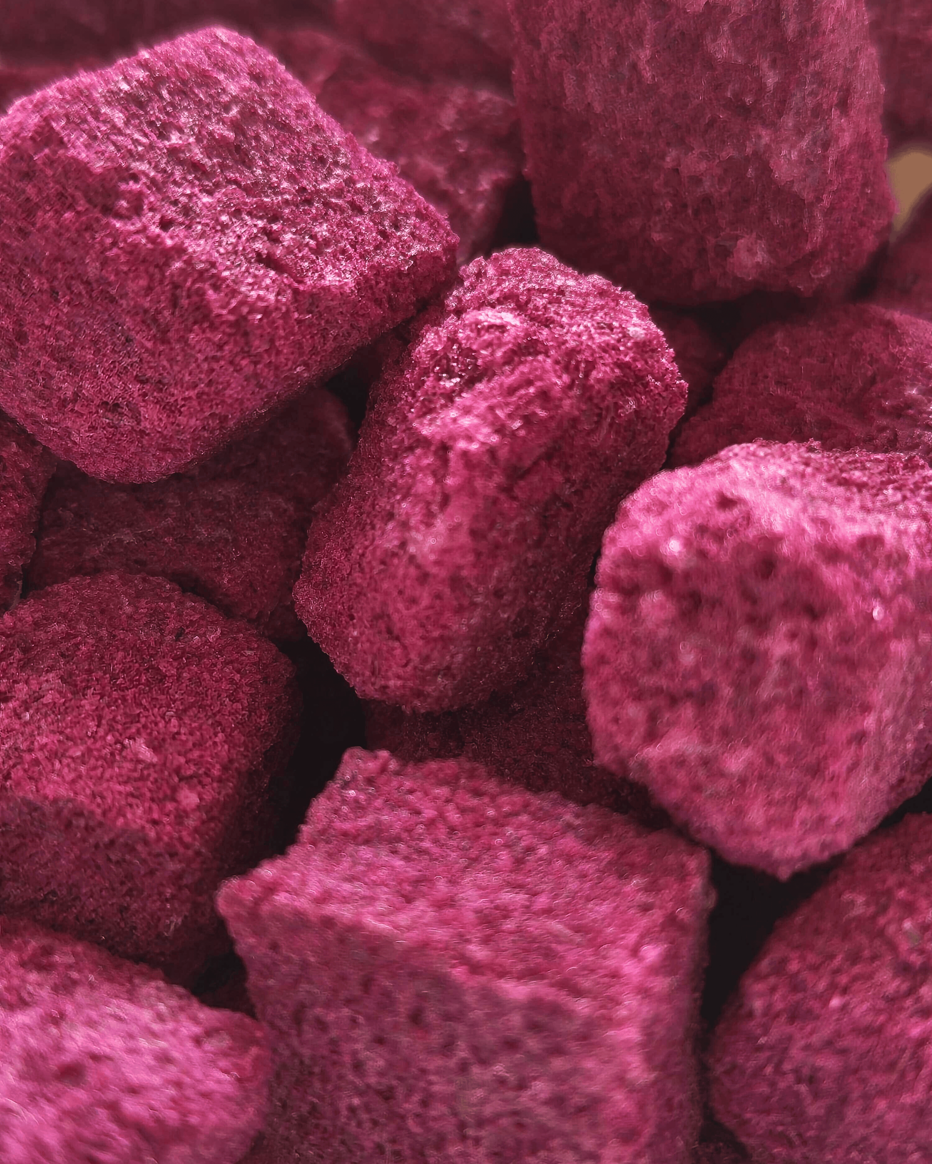 Close-up image of vibrant, textured, deep pink or purple freeze-dried cubes.