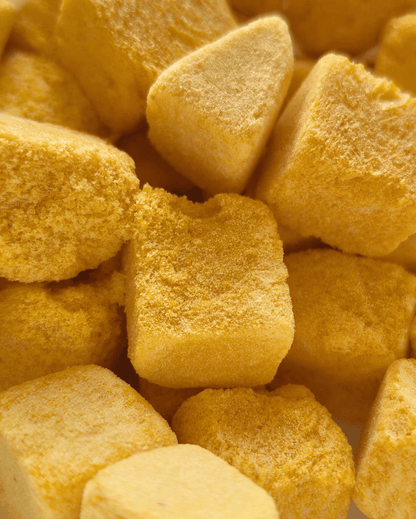 Close-up of several Moon Freeze Dried Mango Cubes by Themoonstoreindia, with a rough texture and bright yellow hue, arranged randomly.