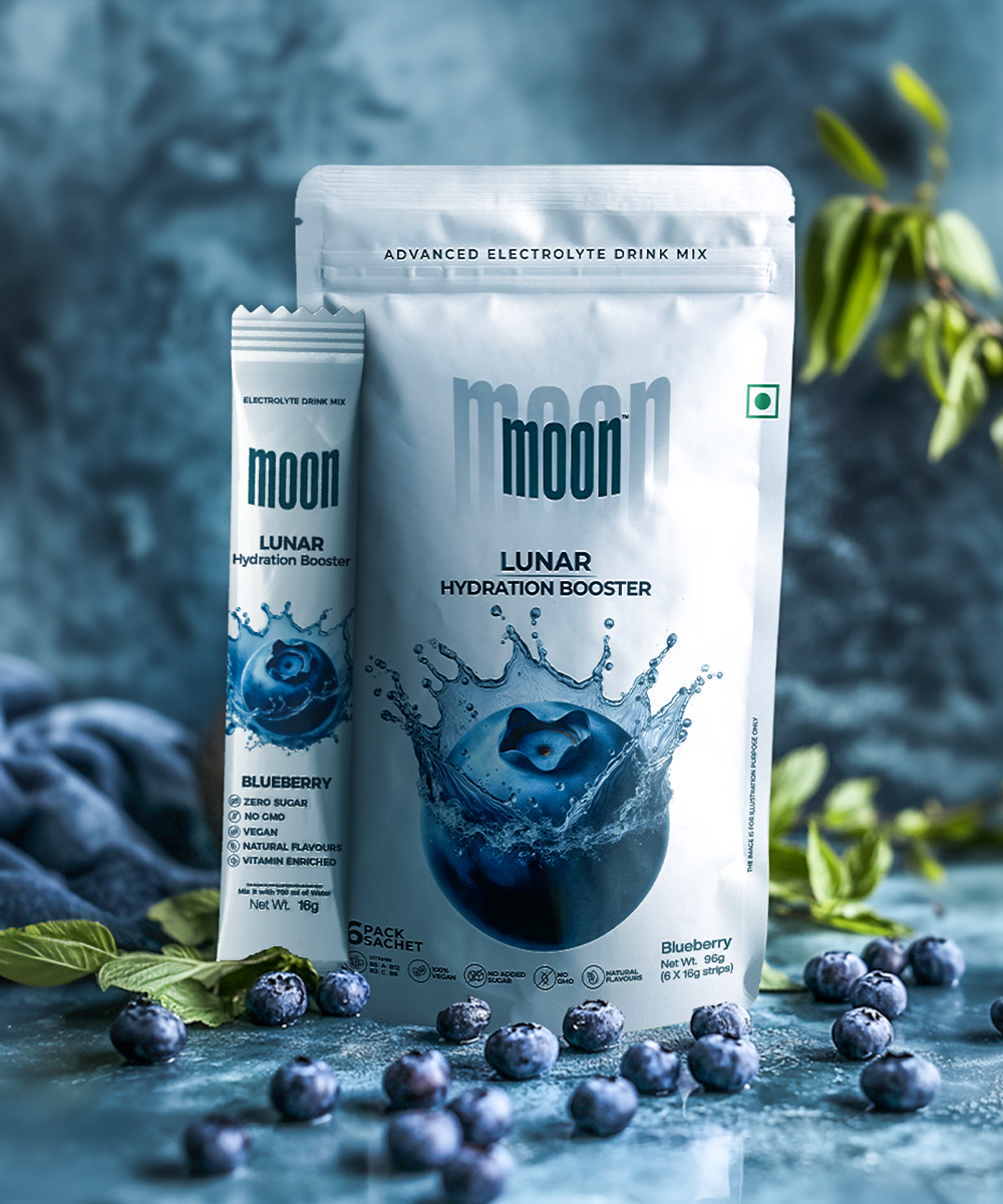 Pouches of Lunar Hydration Booster - Blueberry electrolyte drink mix from MOONFREEZE FOODS PRIVATE LIMITED, featuring essential electrolytes and no added sugar, are displayed with fresh blueberries and green leaves on a blue background.