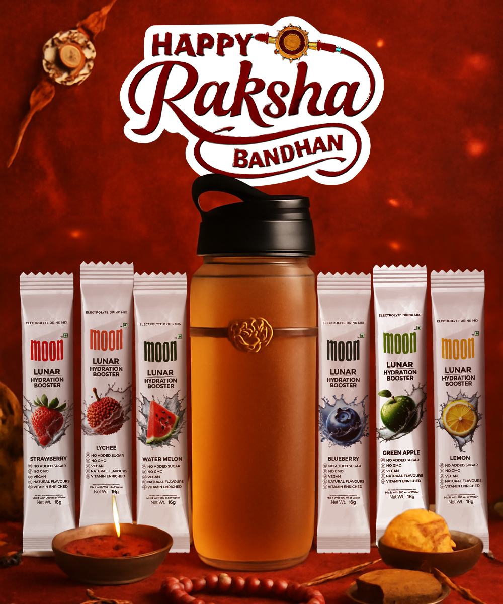 The Lunar Hydration Booster - Variety Pack (With Bottle) by MOONFREEZE FOODS PRIVATE LIMITED features a bottle with an emblem and six assorted sachets, "Happy Raksha Bandhan" above, and traditional items arranged around.