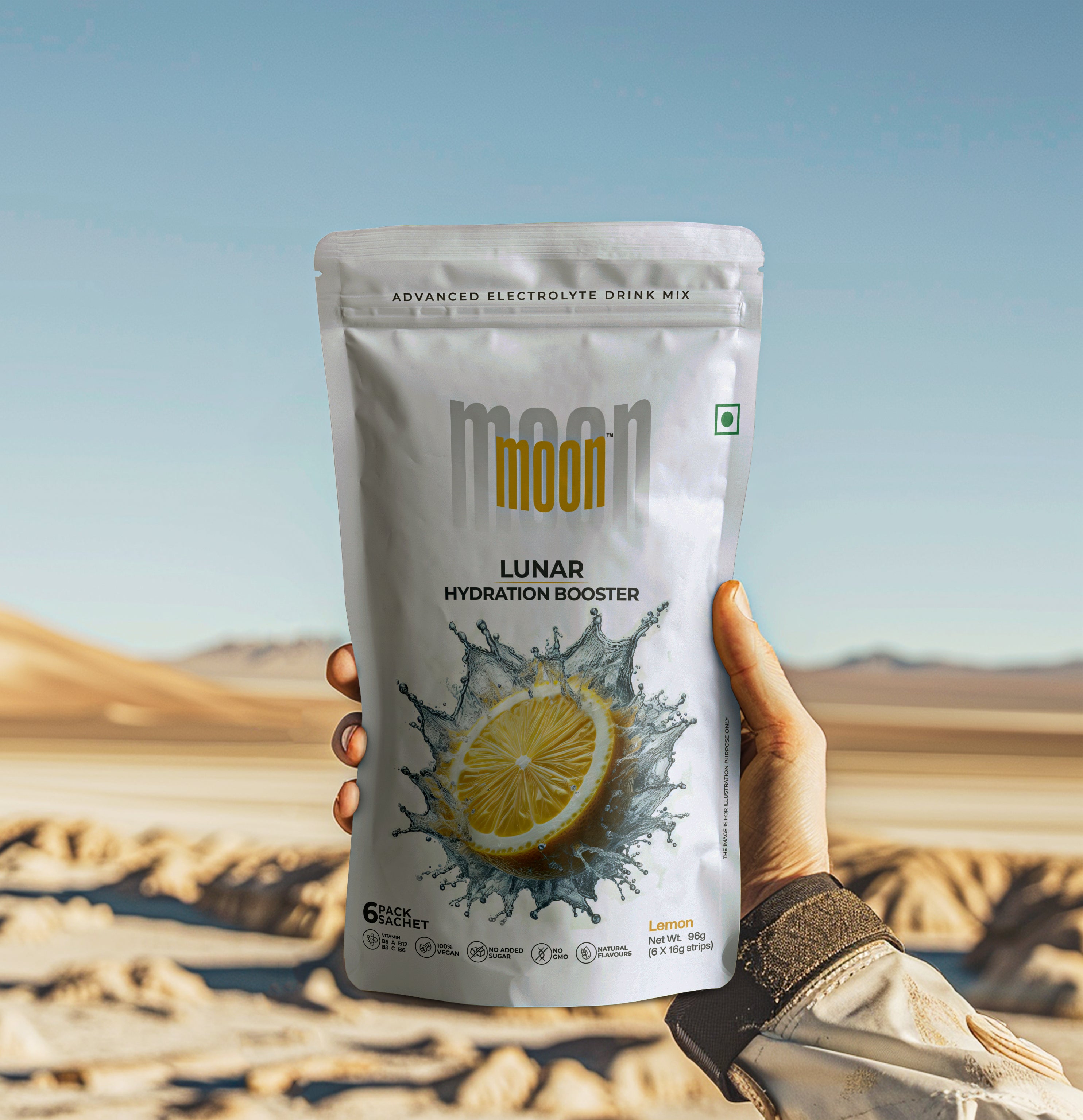 A hand holds a bag of "Lunar Hydration Booster - Lemon," an electrolyte drink mix from MOONFREEZE FOODS PRIVATE LIMITED, adorned with a lemon splash logo, set against a desert landscape background.