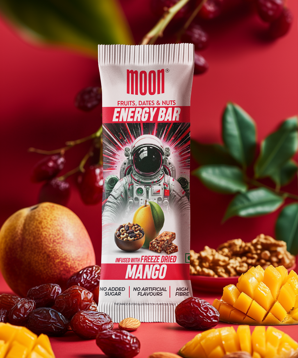 Introducing the MOON Energy Bar - Mango (Single) by MOONFREEZE FOODS PRIVATE LIMITED, an invigorating meal replacement made with freeze-dried mangoes. Set against a vibrant red background adorned with fresh mango, dates, and nuts, its packaging features an astronaut illustration that perfectly embodies the adventurous essence of this delicious bar.