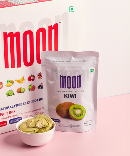 Package of freeze-dried kiwi slices beside a bowl of Moon Freeze Astronaut's Diet Pack - Refresh Edition, with a pink background and a box indicating various fruit options from the MOONFREEZE FOODS PRIVATE LIMITED.