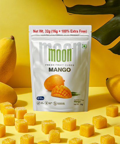A package of Themoonstoreindia Moon Freeze Dried Mango Cubes stands upright among whole mangoes, lush leaves, and scattered cubes on a yellow surface—delicious, healthy snacks packed with antioxidant mangiferin.