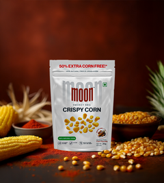 A Freeze Dried Crispy Corn Smokey BBQ bag from MOONFREEZE FOODS PRIVATE LIMITED rests among corn cobs on a red textured background. Ideal for BBQ fans, the label boasts 50% extra corn free.