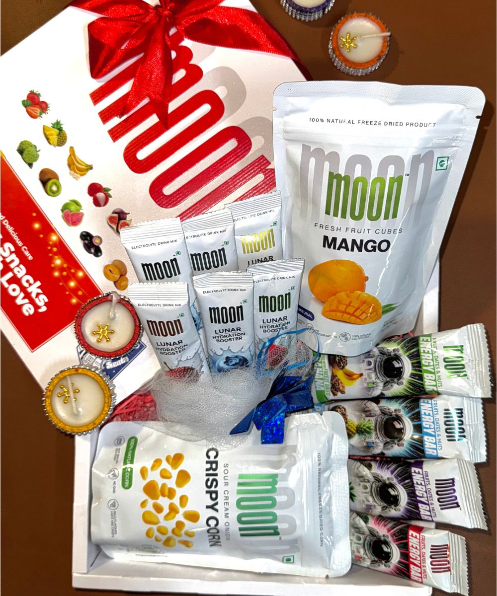 The Festive Feast Hamper by MOONFREEZE FOODS PRIVATE LIMITED includes an assortment of delectable treats such as Lunar Sticks, crispy candies, and energy bars, along with decorative items and a gift card.