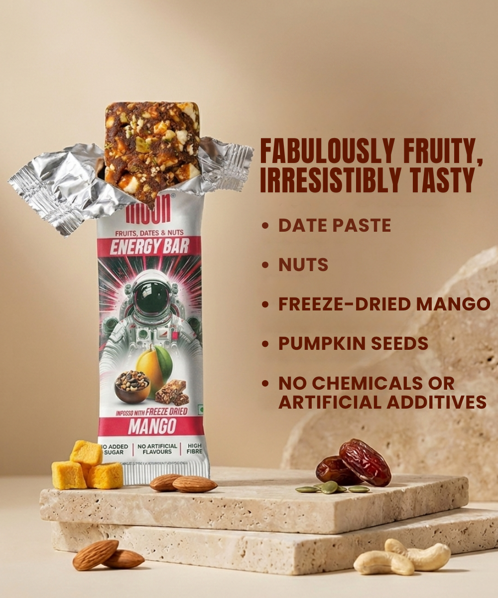 The MOON Energy Bar - Mango by MOONFREEZE FOODS PRIVATE LIMITED is shown in silver packaging with ingredients—nuts, dates, and freeze-dried mango—on a beige surface, plus meal replacement details and product features.