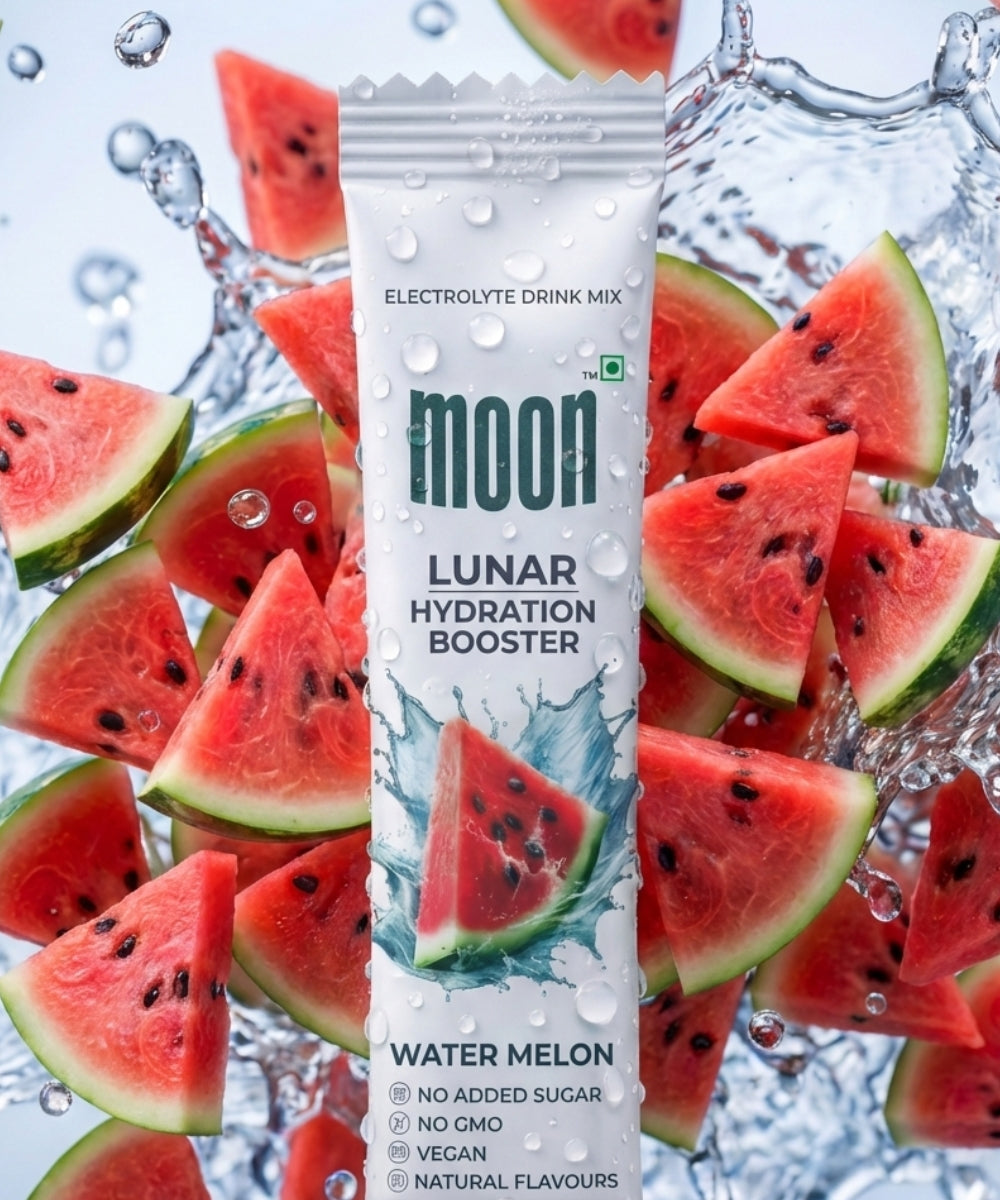 A packet of Lunar Hydration Booster - Watermelon by MOONFREEZE FOODS PRIVATE LIMITED stands upright amid splashing watermelon slices and water droplets, emphasizing its essential electrolytes and energizing B vitamins.
